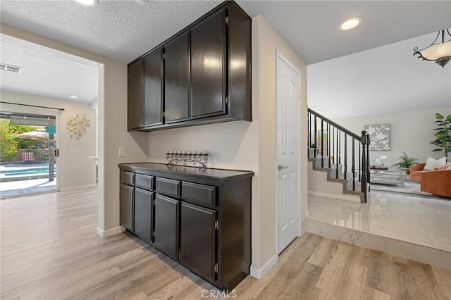 78675 Bradford Cir, La Quinta, CA 92253 - interior space featuring baseboards, stairway, light wood-style flooring, a textured ceiling, and visible vents