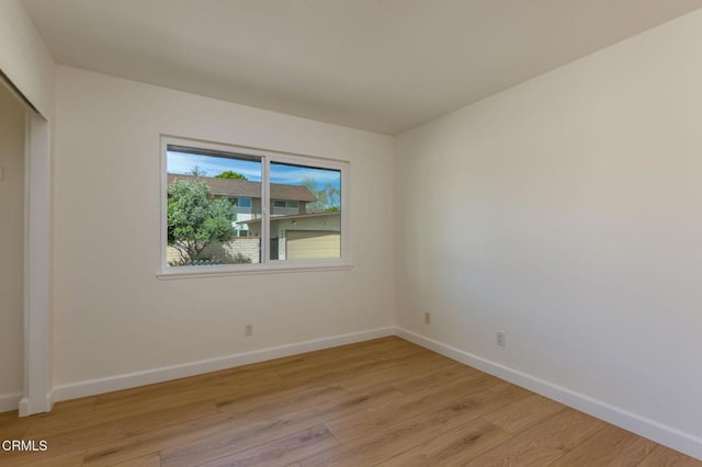 spare room with baseboards and light wood-style floors