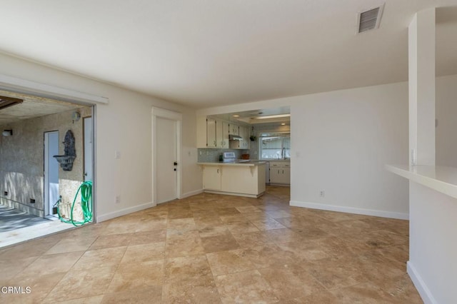 unfurnished living room with visible vents, baseboards, and a sink