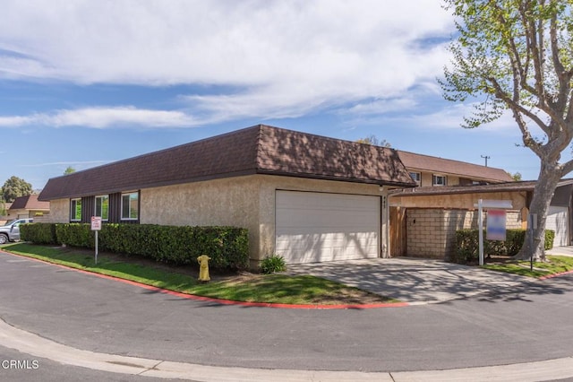 multi unit property featuring driveway, a garage, stucco siding, a shingled roof, and mansard roof