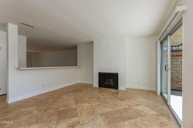unfurnished living room featuring a fireplace, baseboards, stone finish floor, and visible vents