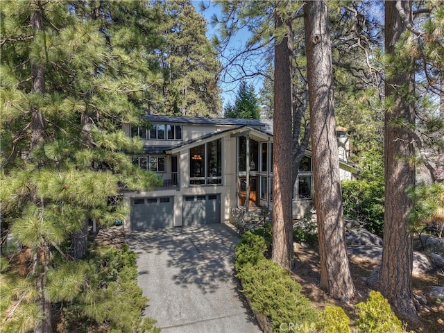 28018 Peninsula, Lake Arrowhead, CA 92352 - view of front facade featuring concrete driveway, an attached garage, and a sunroom