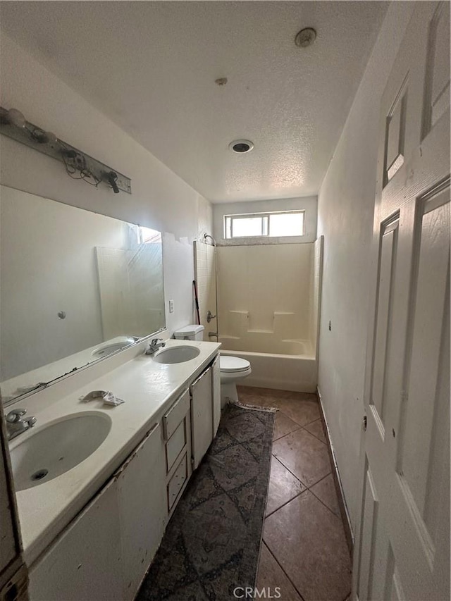 bathroom with a sink, tile patterned floors, toilet, and double vanity