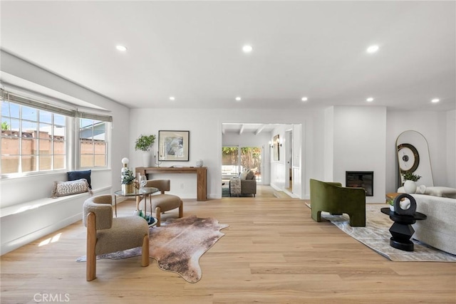 living room with recessed lighting, a glass covered fireplace, and light wood finished floors