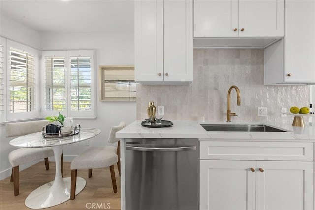kitchen with backsplash, wood finished floors, dishwasher, a sink, and white cabinets