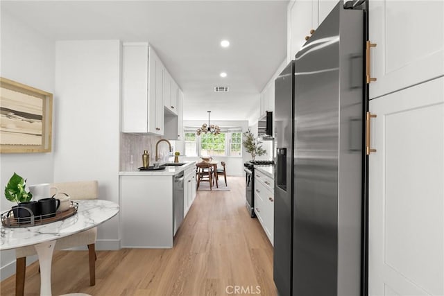13807 Wyandotte St, Van Nuys, CA 91405 - kitchen with appliances with stainless steel finishes, a sink, light wood-style floors, white cabinets, and light countertops
