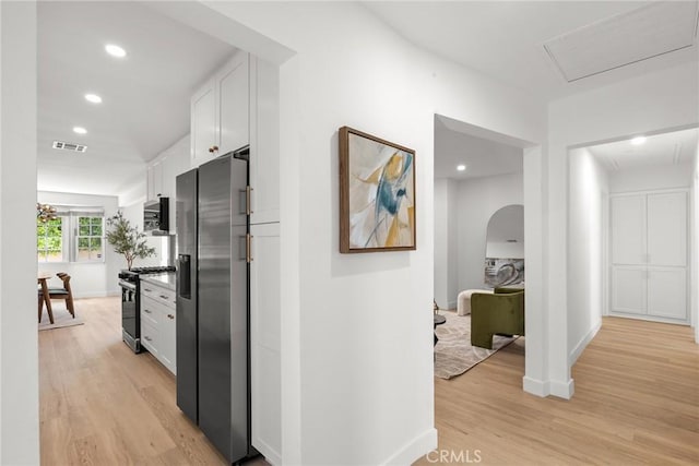 corridor with baseboards, visible vents, and light wood finished floors