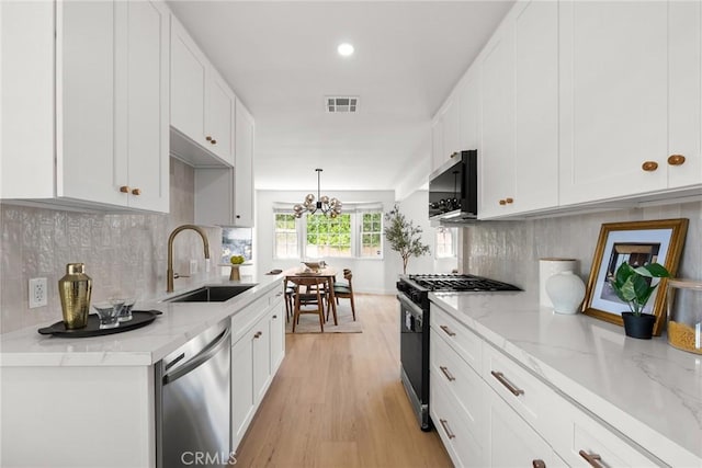 kitchen with white cabinets, appliances with stainless steel finishes, a sink, light wood-style floors, and visible vents