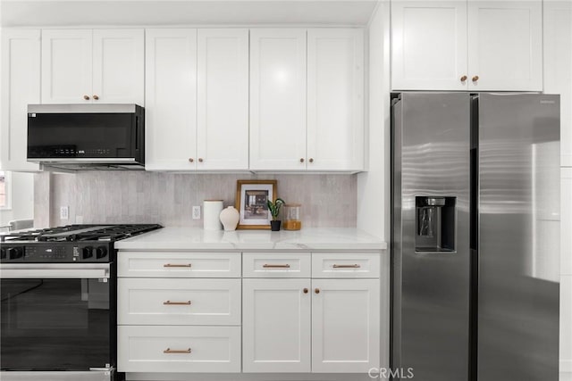 kitchen featuring stainless steel refrigerator with ice dispenser, gas range, tasteful backsplash, light stone counters, and white cabinetry
