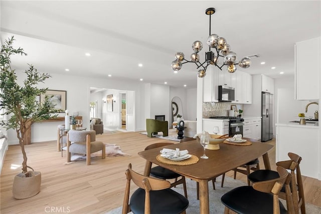 dining area featuring light wood-style floors, recessed lighting, and an inviting chandelier