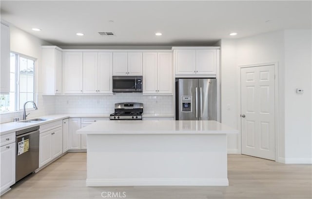 kitchen with a center island, white cabinets, visible vents, appliances with stainless steel finishes, and a sink