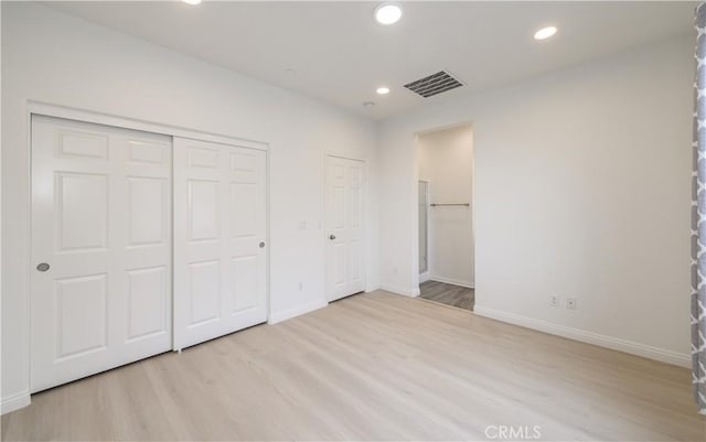 unfurnished bedroom with a closet, baseboards, recessed lighting, visible vents, and wood finished floors