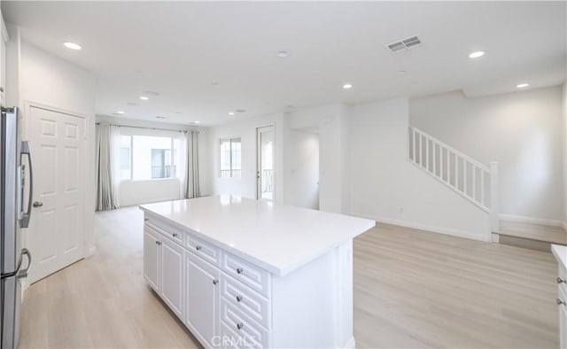 kitchen featuring freestanding refrigerator, light wood-type flooring, visible vents, recessed lighting, and a kitchen island