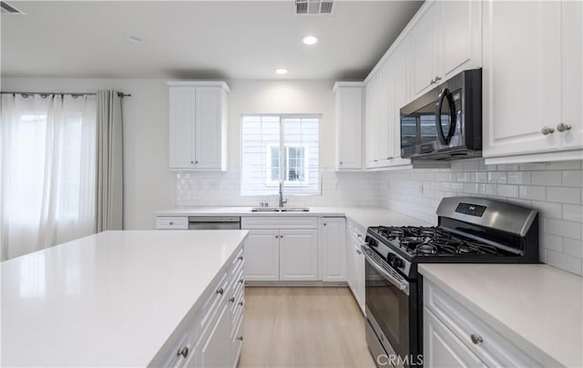 kitchen featuring black microwave, visible vents, gas stove, light countertops, and a sink