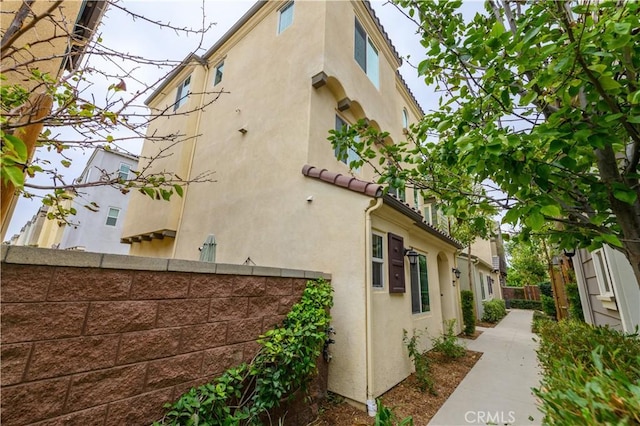 view of property exterior with stucco siding and fence