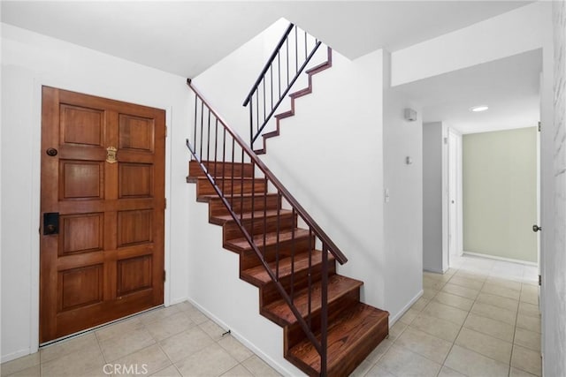 foyer entrance featuring stairs, baseboards, and light tile patterned flooring