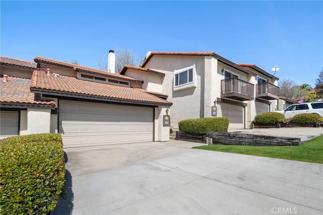 mediterranean / spanish-style home featuring a tiled roof, concrete driveway, and stucco siding