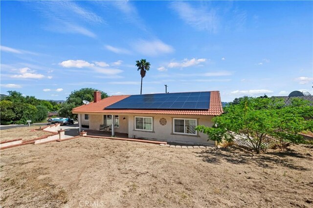 15160 Darnell Dr, Lake Elsinore, CA 92530 - back of house with a tiled roof, roof mounted solar panels, stucco siding, and a chimney