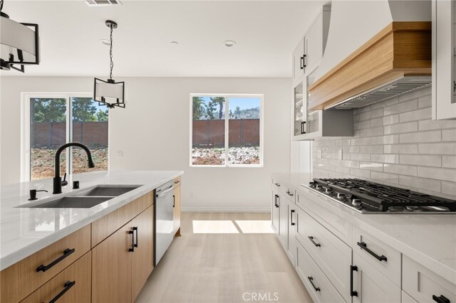 5978 Copperfield Ave, Riverside, CA 92506 - kitchen with a sink, appliances with stainless steel finishes, custom exhaust hood, backsplash, and light stone countertops