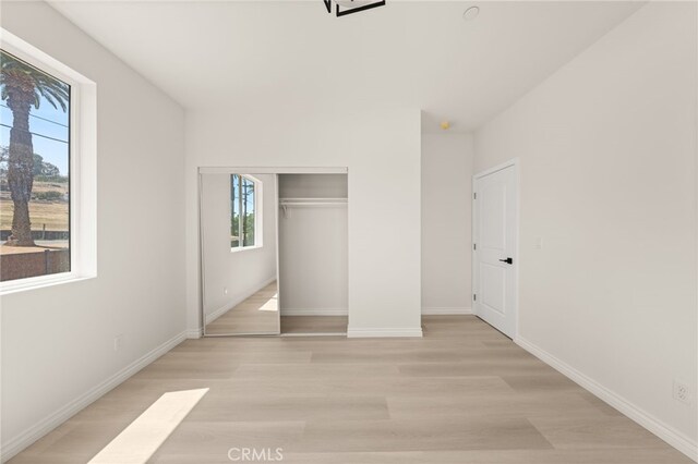 5978 Copperfield Ave, Riverside, CA 92506 - unfurnished bedroom featuring multiple windows, light wood-style floors, baseboards, and a closet