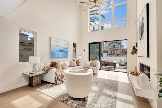 607 12th St, Huntington Beach, CA 92648 - living area featuring wood finished floors, a towering ceiling, a chandelier, baseboards, and a glass covered fireplace