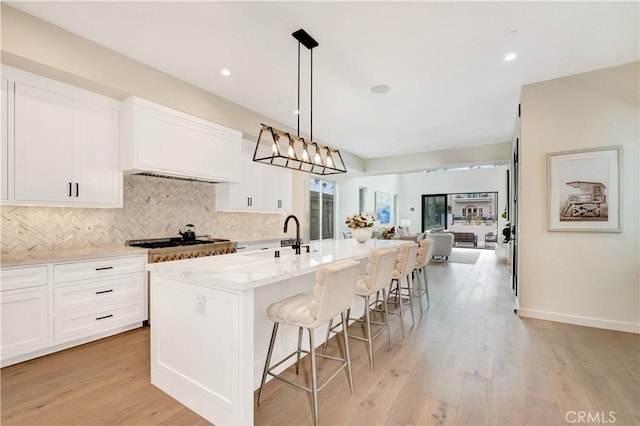 607 12th St, Huntington Beach, CA 92648 - kitchen with decorative backsplash, stainless steel gas stovetop, white cabinets, a kitchen island with sink, and recessed lighting