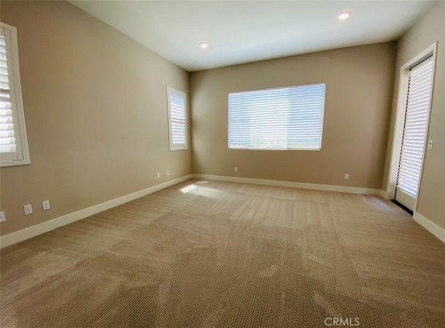 spare room featuring baseboards, recessed lighting, and light colored carpet