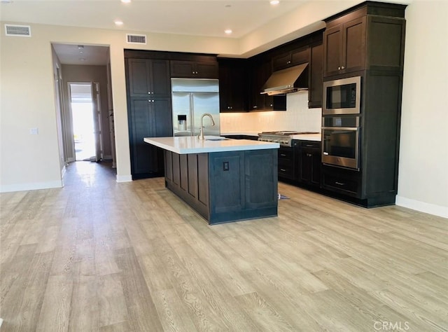 kitchen with under cabinet range hood, built in appliances, visible vents, and light countertops