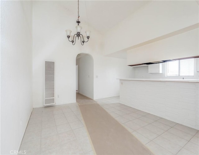 unfurnished dining area featuring arched walkways, light tile patterned floors, high vaulted ceiling, an inviting chandelier, and a heating unit