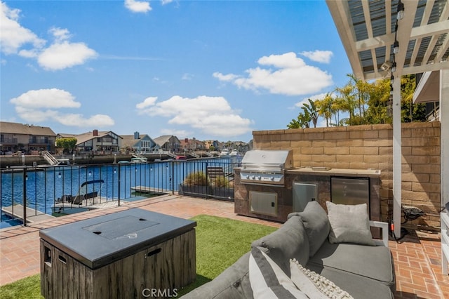 view of patio / terrace featuring an outdoor kitchen, a hot tub, a water view, grilling area, and fence