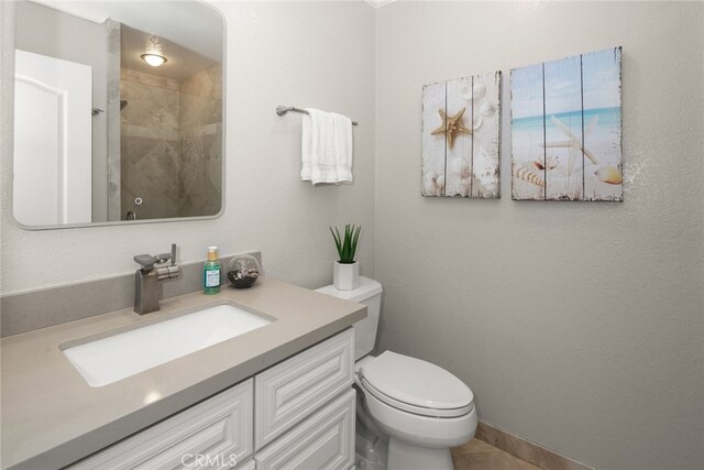 full bathroom with tiled shower, vanity, and toilet