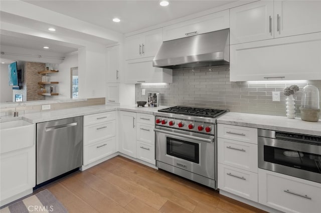 kitchen with under cabinet range hood, light stone counters, white cabinets, and stainless steel appliances