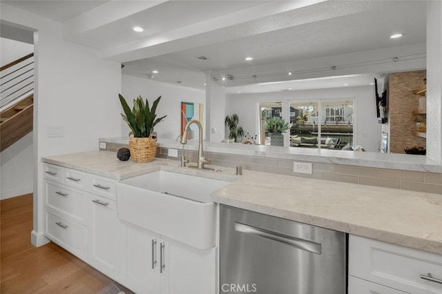kitchen with light wood-style flooring, light stone counters, dishwasher, and a sink