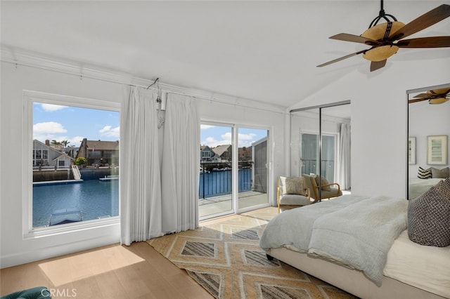 bedroom featuring access to outside, multiple windows, vaulted ceiling, and wood finished floors