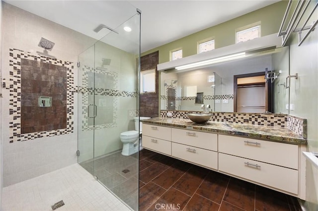 full bathroom featuring vanity, wood finish floors, toilet, a shower stall, and decorative backsplash