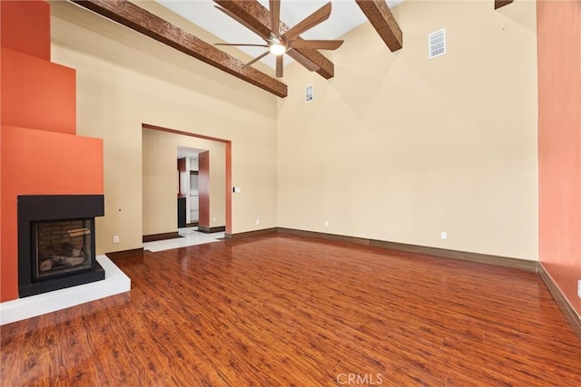unfurnished living room featuring beamed ceiling, a ceiling fan, visible vents, wood finished floors, and baseboards