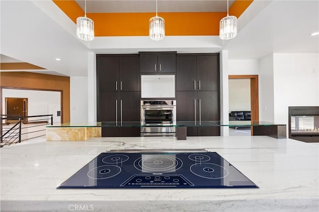 kitchen with light stone counters, decorative light fixtures, black electric cooktop, and stainless steel double oven