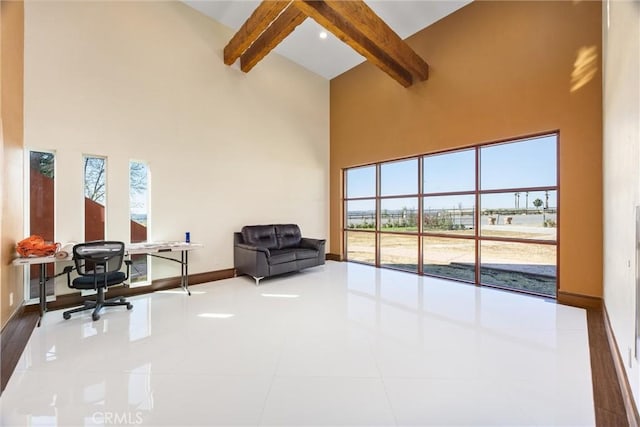 office featuring baseboards, a high ceiling, beamed ceiling, and a healthy amount of sunlight