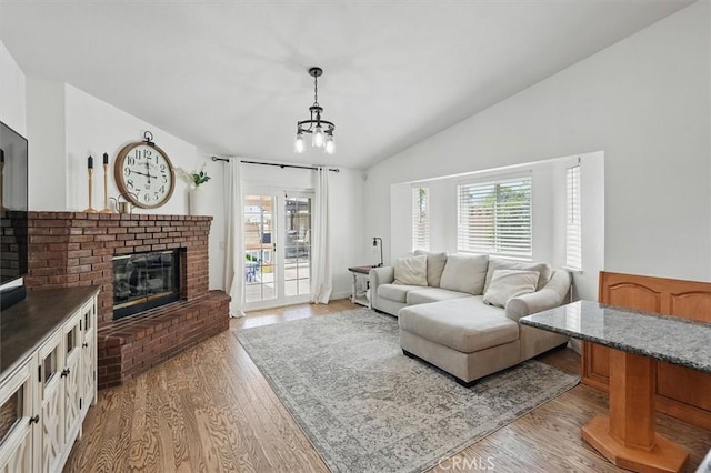 42370 61st St W, Lancaster, CA 93536 - living area featuring vaulted ceiling, a fireplace, a chandelier, and light wood-style floors