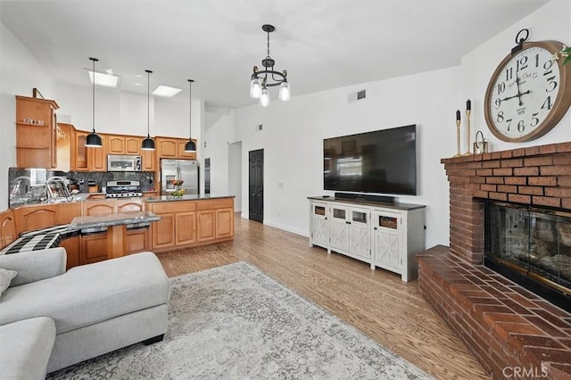 42370 61st St W, Lancaster, CA 93536 - living room with light wood-type flooring, a brick fireplace, a chandelier, and a high ceiling