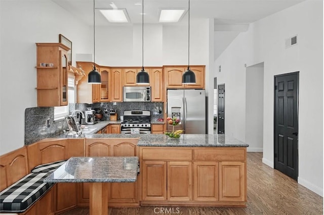 42370 61st St W, Lancaster, CA 93536 - kitchen featuring stainless steel appliances, high vaulted ceiling, decorative backsplash, stone countertops, and a peninsula