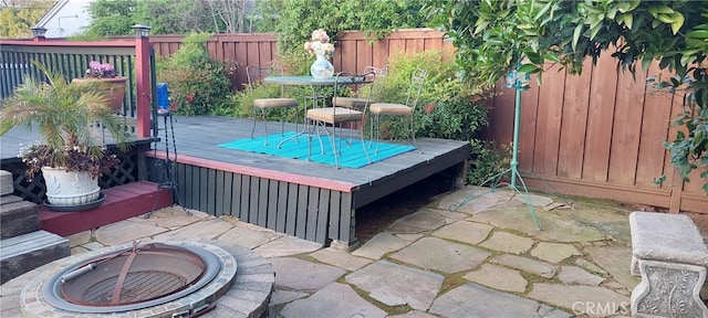deck featuring a fenced backyard and a fire pit