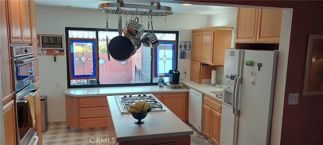 kitchen featuring light countertops, stainless steel appliances, light brown cabinets, and a center island