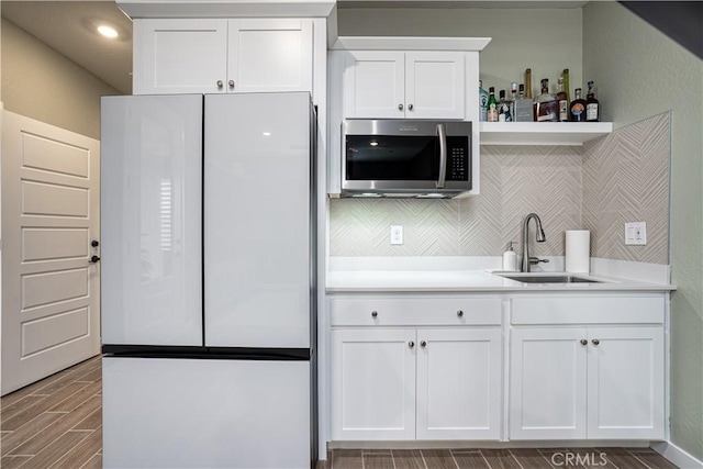1093 Traverse Dr S, Madera, CA 93636 - kitchen with wood finish floors, a sink, freestanding refrigerator, stainless steel microwave, and white cabinetry