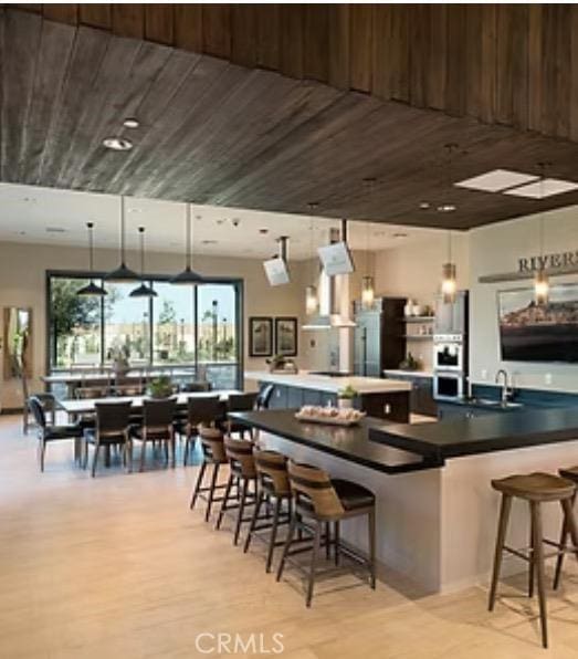 1093 Traverse Dr S, Madera, CA 93636 - kitchen featuring a kitchen breakfast bar, stainless steel oven, pendant lighting, and light wood-style floors
