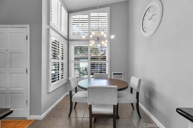 tiled dining space with a high ceiling, baseboards, and an inviting chandelier