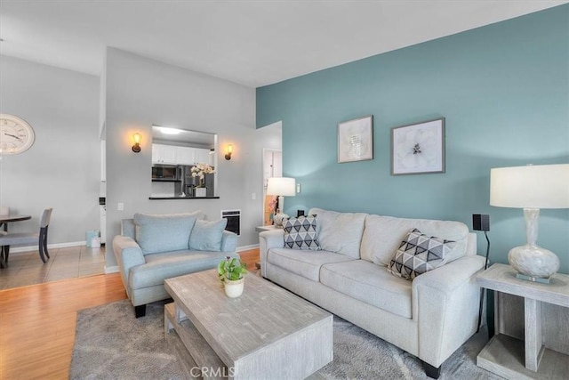 living room with light wood-type flooring, baseboards, and heating unit