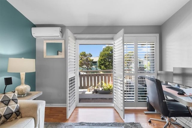 office area featuring an AC wall unit, baseboards, wood finished floors, and a healthy amount of sunlight