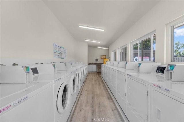 community laundry room with light wood-style floors and independent washer and dryer