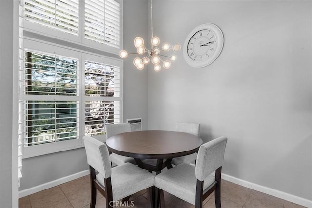 dining area featuring tile patterned flooring, a towering ceiling, baseboards, and an inviting chandelier